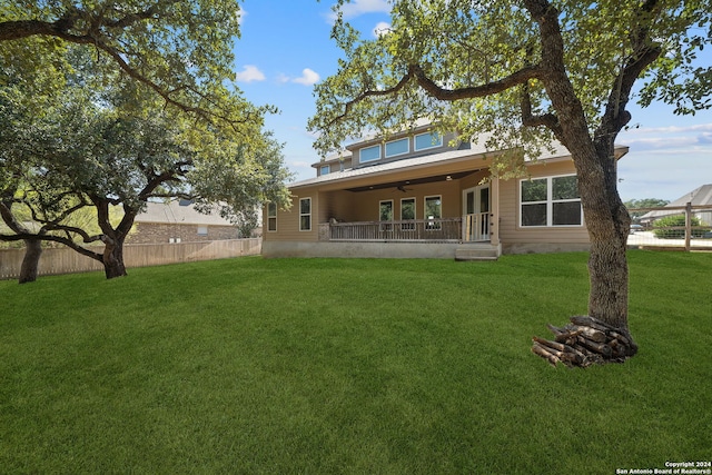 back of property with ceiling fan and a lawn