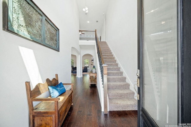 interior space with a towering ceiling, a notable chandelier, and dark wood-type flooring