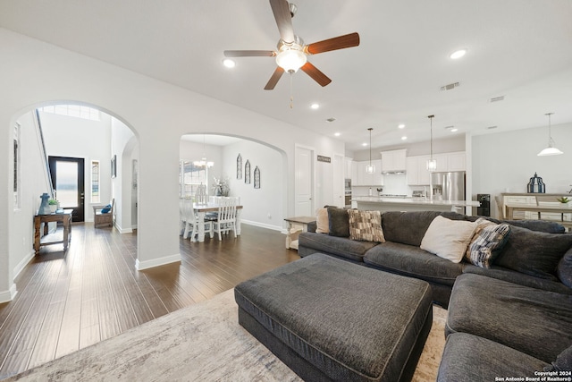 living room featuring dark hardwood / wood-style flooring and ceiling fan with notable chandelier