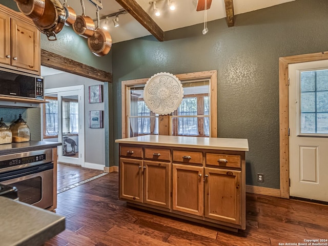 kitchen with stainless steel appliances, dark hardwood / wood-style floors, beamed ceiling, track lighting, and ceiling fan