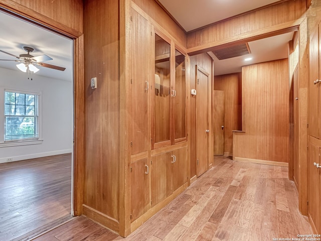 mudroom featuring ceiling fan, light hardwood / wood-style flooring, and wood walls