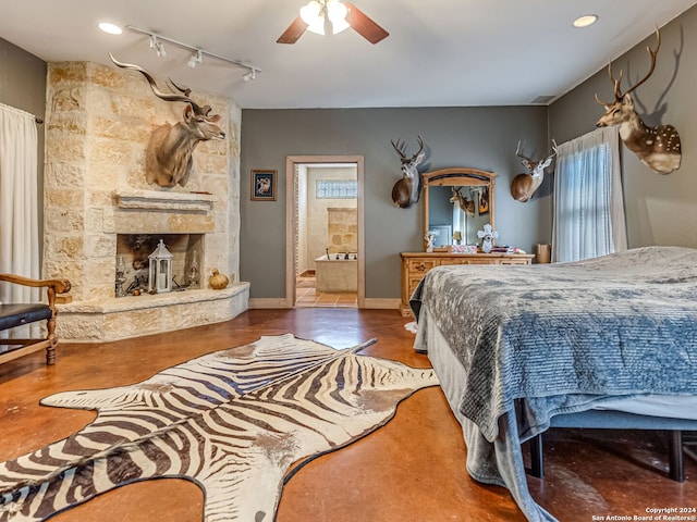 tiled bedroom featuring ceiling fan, a stone fireplace, track lighting, and multiple windows