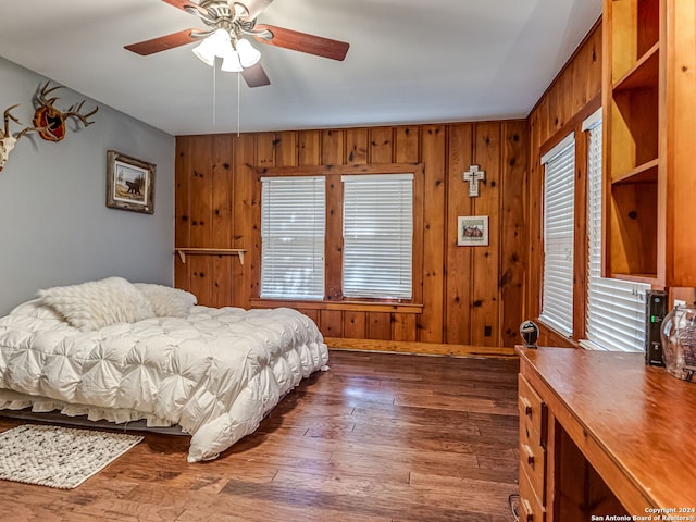 bedroom with wooden walls, ceiling fan, and dark hardwood / wood-style flooring