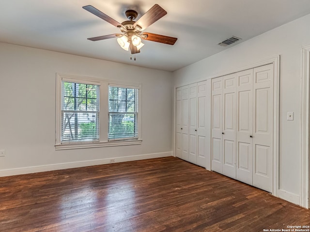 unfurnished bedroom featuring ceiling fan, a closet, and dark wood-type flooring