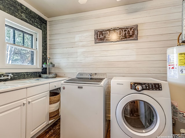 laundry area with wooden walls, water heater, separate washer and dryer, and cabinets