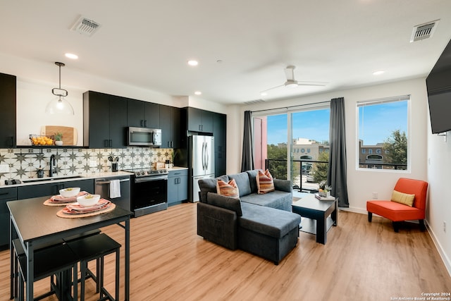 kitchen featuring ceiling fan, light wood-type flooring, backsplash, appliances with stainless steel finishes, and sink