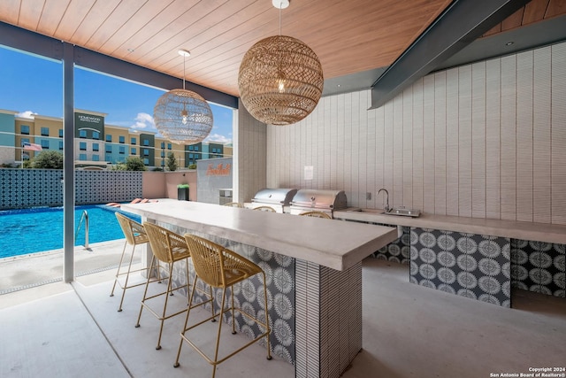 interior space featuring wood ceiling, a kitchen breakfast bar, a sink, and decorative light fixtures