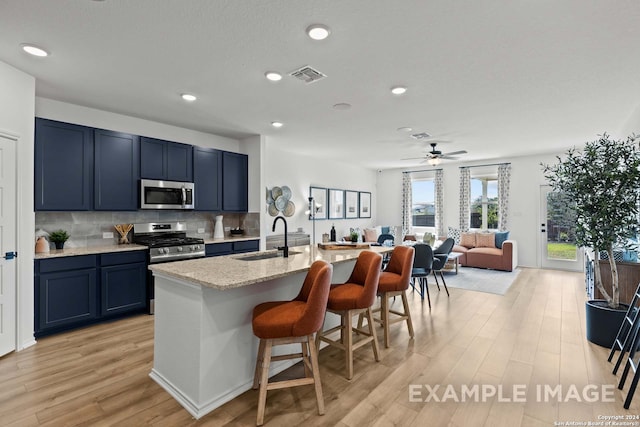 kitchen with a kitchen breakfast bar, light stone countertops, light hardwood / wood-style flooring, and stainless steel appliances