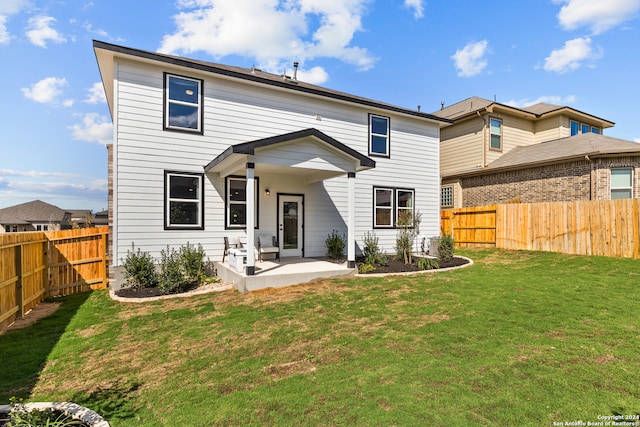 back of house featuring a patio area and a lawn