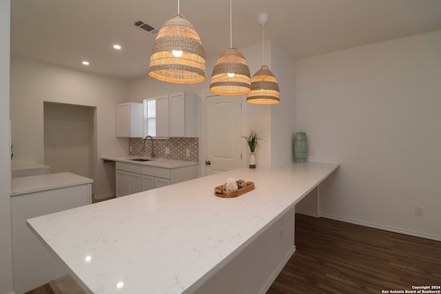 kitchen featuring backsplash, sink, dark hardwood / wood-style flooring, pendant lighting, and white cabinets