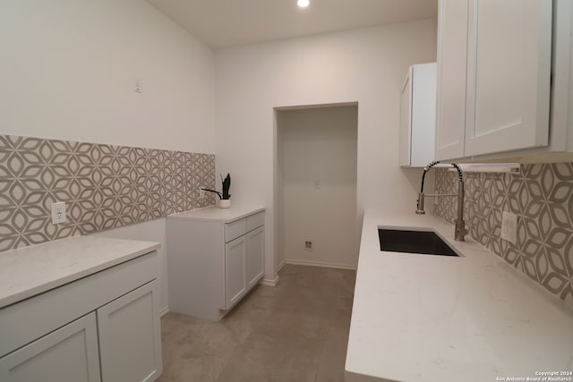 kitchen featuring sink, decorative backsplash, light tile patterned floors, and white cabinets