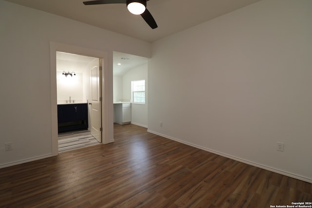 empty room with ceiling fan, lofted ceiling, sink, and dark wood-type flooring