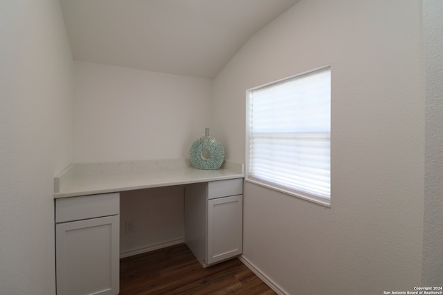 unfurnished office with dark wood-type flooring, vaulted ceiling, and built in desk