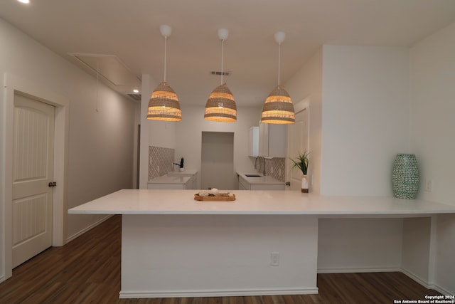 kitchen featuring kitchen peninsula, pendant lighting, dark wood-type flooring, and a kitchen breakfast bar