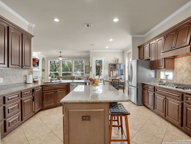 kitchen featuring sink, a center island, decorative backsplash, light tile patterned floors, and stainless steel appliances