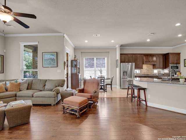 living room with crown molding, dark wood-style flooring, visible vents, and plenty of natural light