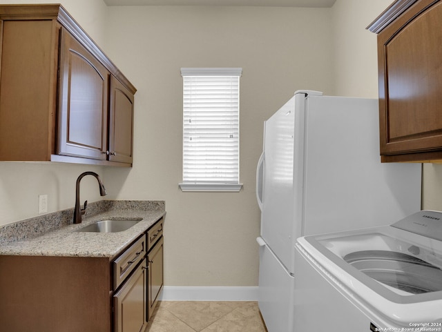 washroom with washer / clothes dryer, a wealth of natural light, sink, and light tile patterned flooring