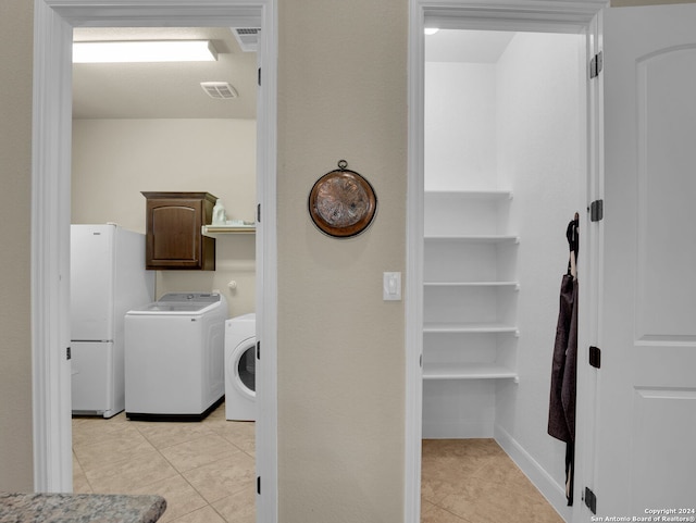 washroom featuring light tile patterned flooring, washing machine and dryer, and cabinets