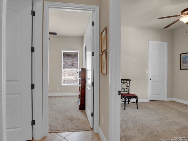 corridor with baseboards and light colored carpet