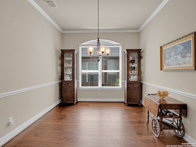 dining area with hardwood / wood-style flooring, ornamental molding, and a chandelier