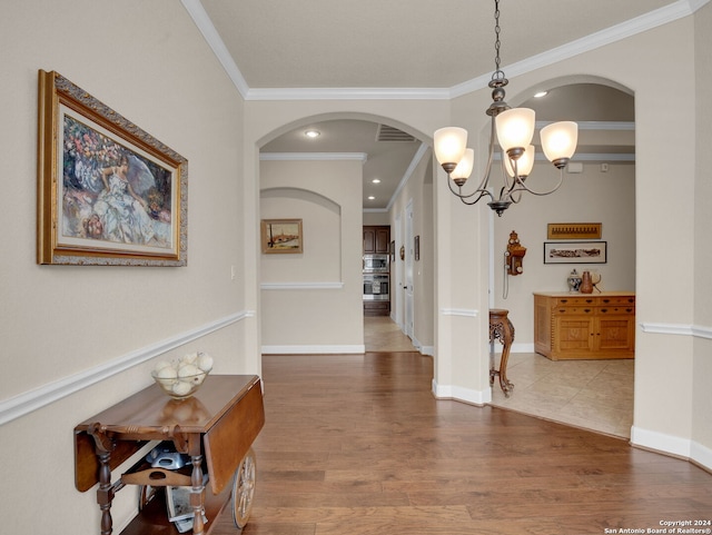 interior space with wood finished floors, visible vents, baseboards, an inviting chandelier, and crown molding