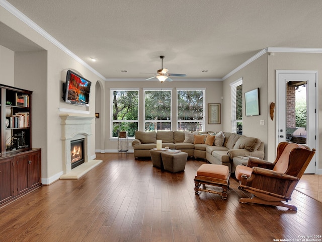 living room with a textured ceiling, ceiling fan, hardwood / wood-style floors, and ornamental molding