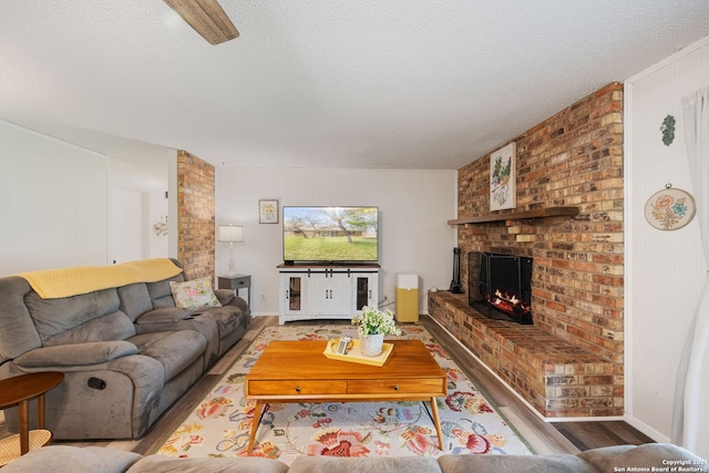 living room featuring hardwood / wood-style flooring, a textured ceiling, a brick fireplace, and brick wall