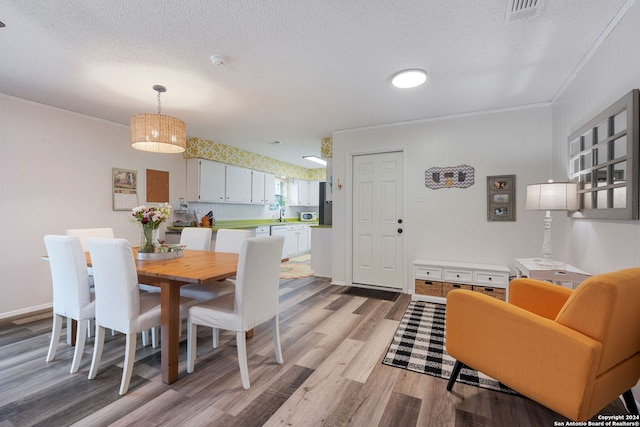 dining area featuring hardwood / wood-style flooring, crown molding, and a textured ceiling