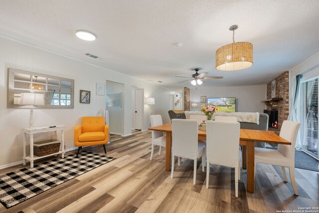 dining space with a ceiling fan, a textured ceiling, baseboards, light wood finished floors, and ornamental molding