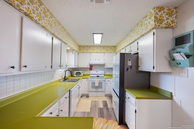 kitchen with white appliances, a textured ceiling, a sink, light wood-style flooring, and backsplash