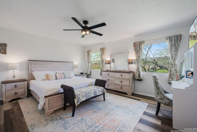 bedroom featuring a textured ceiling, multiple windows, and wood finished floors
