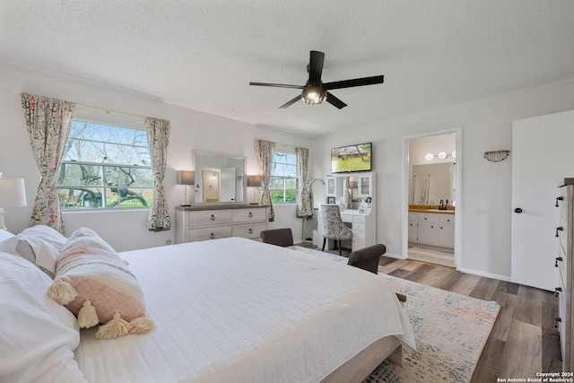 bedroom featuring light wood-type flooring, ceiling fan, a textured ceiling, and ensuite bath