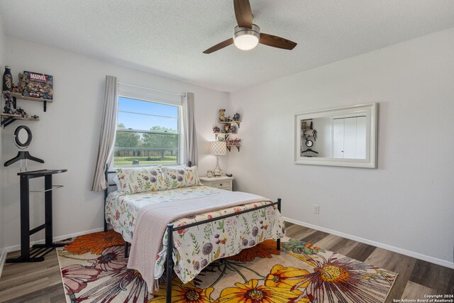 bedroom featuring baseboards, a textured ceiling, ceiling fan, and wood finished floors