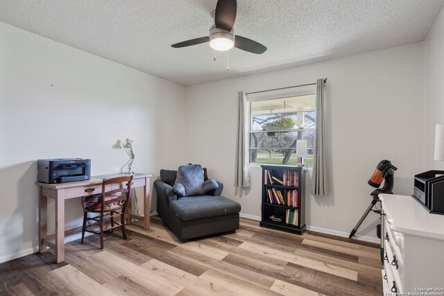 office with a textured ceiling, baseboards, a ceiling fan, and light wood-style flooring