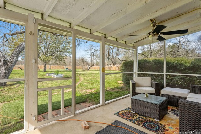 sunroom / solarium with a ceiling fan and beam ceiling