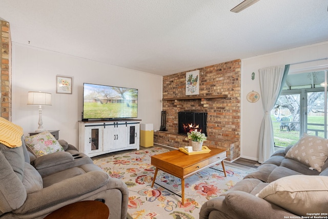 living room featuring hardwood / wood-style flooring, a textured ceiling, a brick fireplace, and brick wall