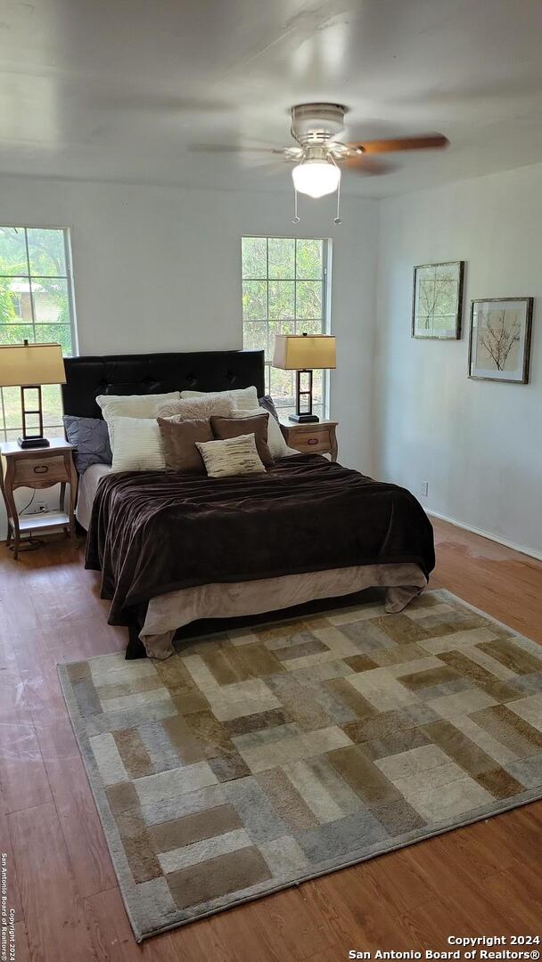 bedroom with ceiling fan, hardwood / wood-style floors, and multiple windows