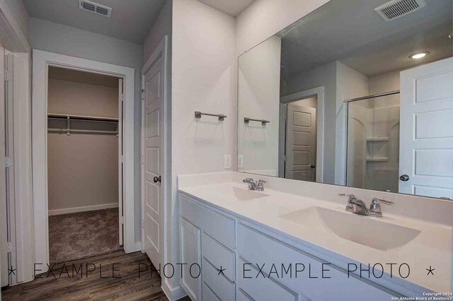 bathroom featuring a shower with shower door, wood-type flooring, and vanity