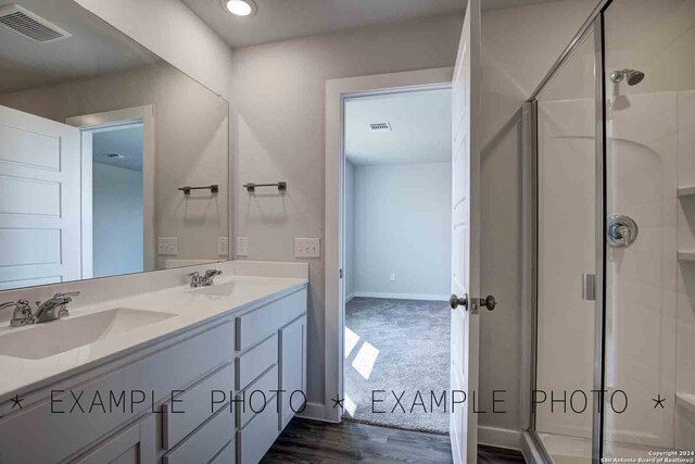 bathroom with hardwood / wood-style floors, vanity, and a shower with door