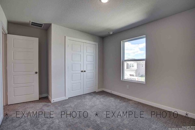 unfurnished bedroom featuring carpet, a textured ceiling, and a closet