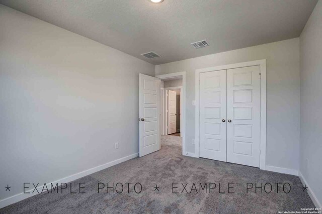 unfurnished bedroom with carpet flooring, a closet, and a textured ceiling