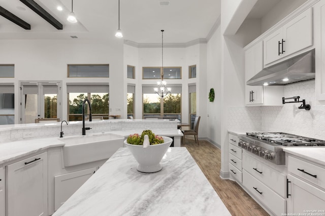 kitchen with backsplash, pendant lighting, stainless steel gas cooktop, light hardwood / wood-style floors, and sink