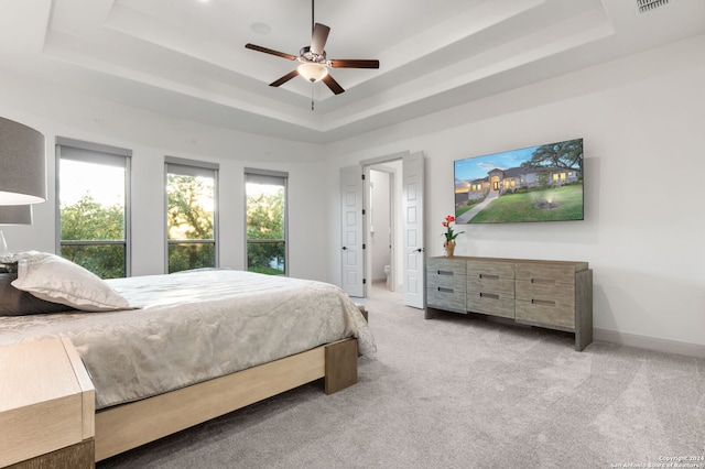 bedroom with ceiling fan, a raised ceiling, and light colored carpet