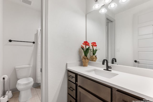 bathroom with toilet, vanity, and tile patterned floors