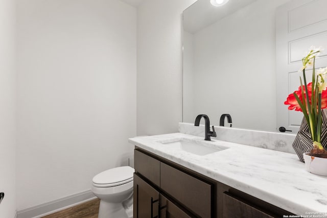 bathroom featuring hardwood / wood-style flooring, toilet, and vanity