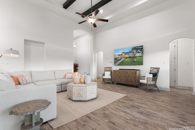 living room featuring a high ceiling, beam ceiling, ceiling fan, and hardwood / wood-style flooring