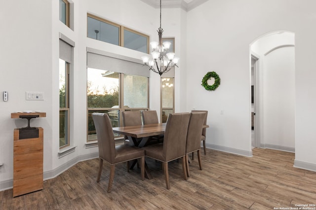 dining area with hardwood / wood-style flooring, a chandelier, and a towering ceiling