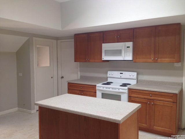 kitchen with a center island, light tile patterned flooring, and white appliances