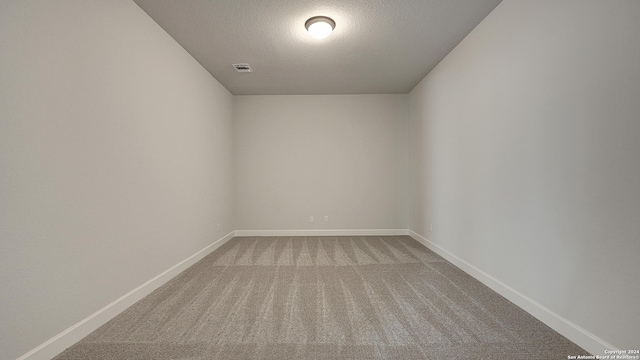 carpeted empty room with a textured ceiling