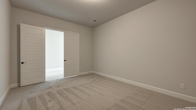 carpeted empty room featuring vaulted ceiling and a textured ceiling